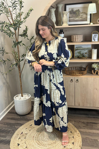 Woman in a blue and white patterned dress standing in a room with decor elements.