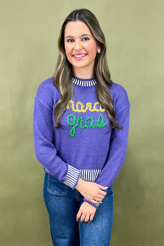 Woman wearing a blue sweater with colorful text on a green background