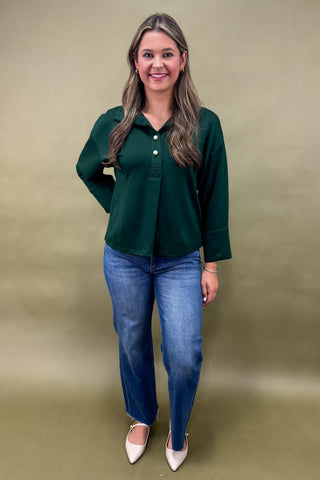 Woman wearing a green blouse and blue jeans against a beige background