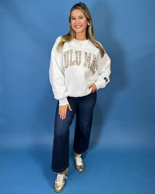 White LULU MAC sweatshirt with camouflage logo lettering, styled with dark wash wide leg jeans.