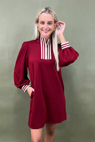 Woman wearing a burgundy dress with white stripes on a green background