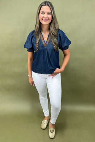 Cream and navy puff sleeve blouse with geometric print styled with light wash wide leg jeans and white sneakers.