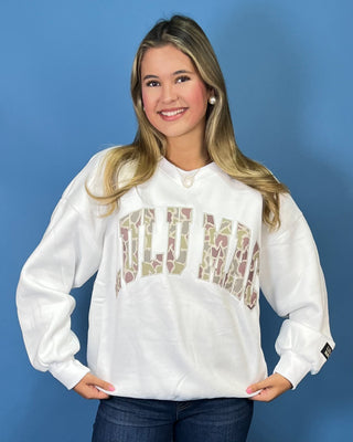 White LULU MAC sweatshirt with camouflage logo lettering, styled with dark wash wide leg jeans.