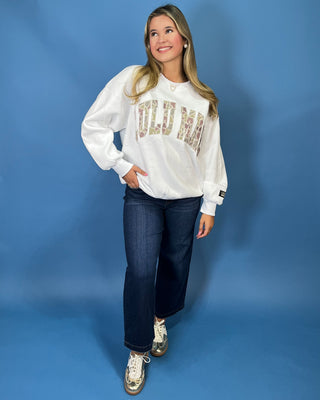 White LULU MAC sweatshirt with camouflage logo lettering, styled with dark wash wide leg jeans.