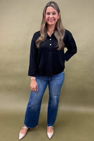 Woman wearing a black shirt and blue jeans against a green background