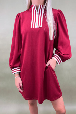 Red dress with white striped collar and cuffs worn by a person against a neutral background