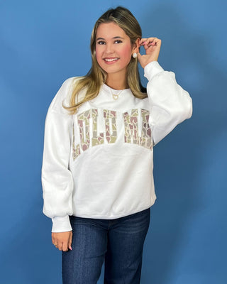 White LULU MAC sweatshirt with camouflage logo lettering, styled with dark wash wide leg jeans.