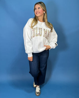 White LULU MAC sweatshirt with camouflage logo lettering, styled with dark wash wide leg jeans.