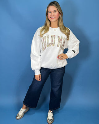 White LULU MAC sweatshirt with camouflage logo lettering, styled with dark wash wide leg jeans.