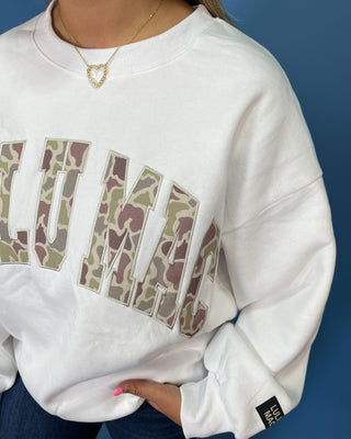 White LULU MAC sweatshirt with camouflage logo lettering, styled with dark wash wide leg jeans.