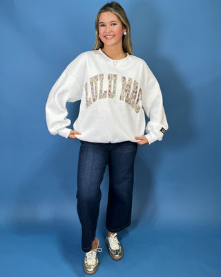 White LULU MAC sweatshirt with camouflage logo lettering, styled with dark wash wide leg jeans.