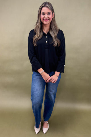 Woman wearing a black shirt and blue jeans against a beige background
