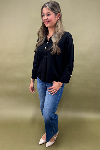 Woman wearing a black shirt and blue jeans against a green background