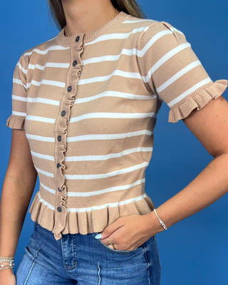 A woman wearing a beige and white horizontally striped short-sleeve knit top with ruffle trim and a button-front closure,