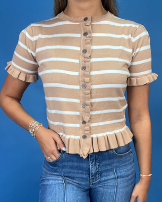 A woman wearing a beige and white horizontally striped short-sleeve knit top with ruffle trim and a button-front closure, pai