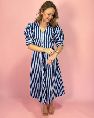 Woman wearing a blue and white striped dress against a pink background
