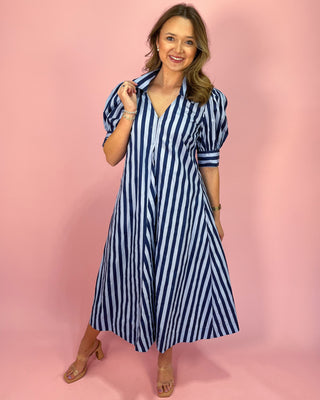 Woman wearing a blue and white striped dress against a pink background