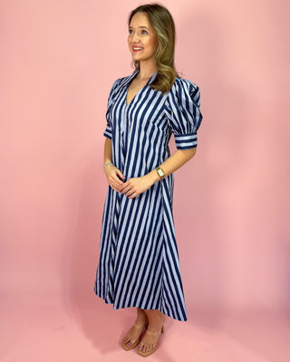 Woman wearing a blue and white striped dress against a pink background