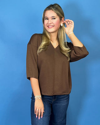 Chocolate brown V-neck three-quarter sleeve top styled with dark wash wide leg jeans and brown flats.