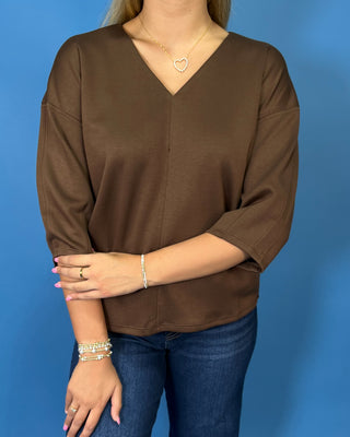 Chocolate brown V-neck three-quarter sleeve top styled with dark wash wide leg jeans and brown flats.