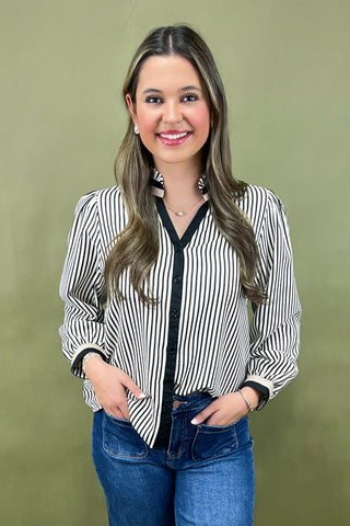 Woman wearing a striped blouse and jeans against a green background