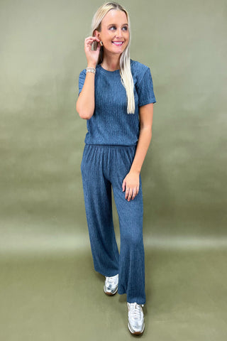 Woman wearing a blue outfit with wide-leg pants on a green background