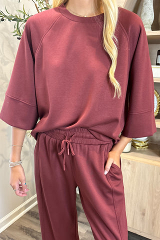 Person wearing a maroon sweatshirt and pants in an indoor setting.