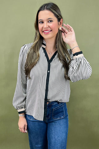 Woman wearing a black and white striped blouse with blue jeans against a green background