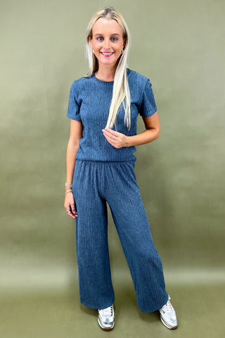 Woman wearing a blue textured outfit against a green background