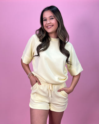 Woman wearing a cream-colored outfit against a pink background