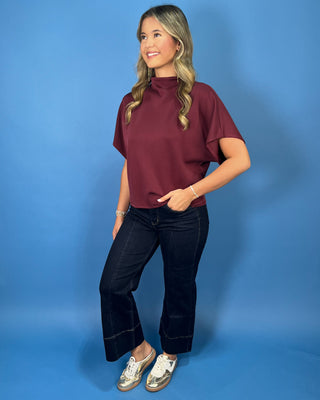 Burgundy mock neck top with relaxed short sleeves and a smooth, polished finish.