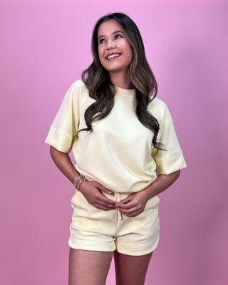Woman wearing a yellow outfit against a pink background