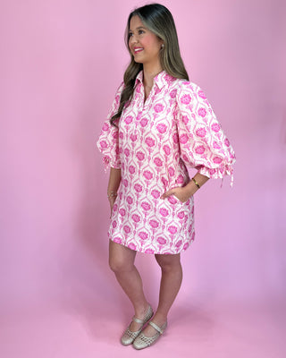 Woman wearing a pink floral dress against a pink background