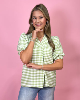 Woman wearing a green checkered blouse against a pink background