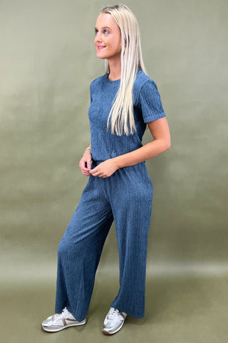 Woman wearing a blue ribbed knit outfit against a green background