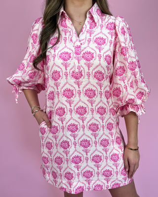 Woman wearing a pink and white patterned dress against a pink background
