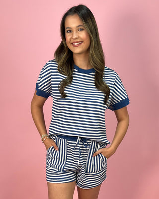 Woman wearing a blue and white striped outfit on a pink background