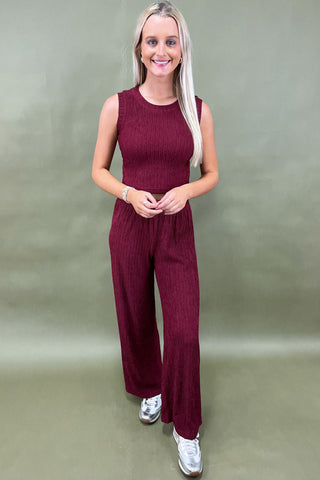 Woman wearing a maroon jumpsuit against a plain background