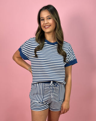 Woman wearing a blue and white striped outfit on a pink background