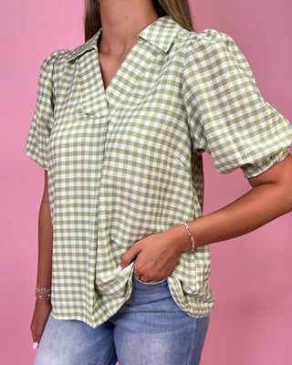 Person wearing a green and white checkered shirt against a pink background