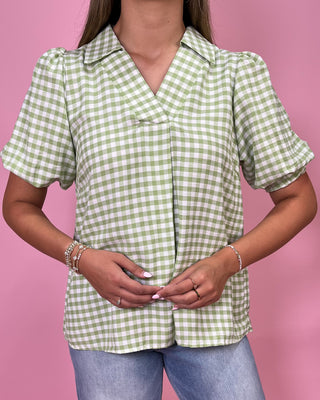 Person wearing a green and white checkered shirt against a pink background