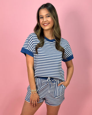Woman wearing a blue and white striped outfit on a pink background