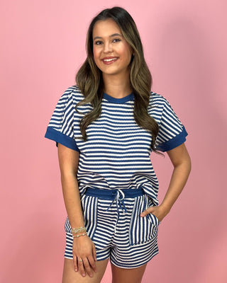 Woman wearing a blue and white striped outfit on a pink background