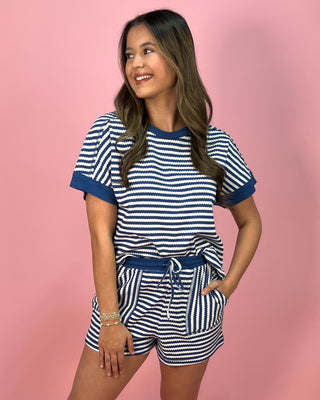 Young girl wearing a blue and white striped outfit on a pink background