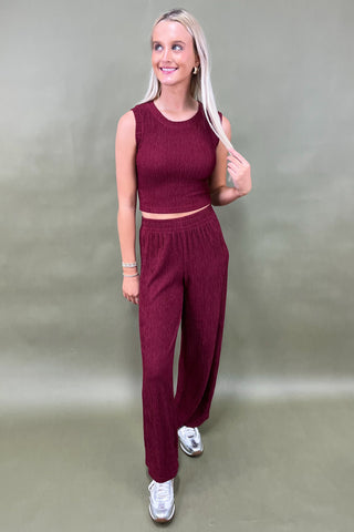 Woman wearing a maroon outfit against a plain background