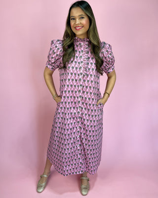 Woman wearing a pink patterned dress against a pink background
