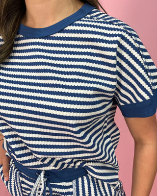 Person wearing a blue and white striped outfit against a pink background