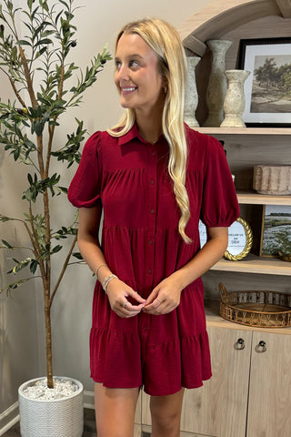 Woman wearing a red dress standing in a room with decor elements.