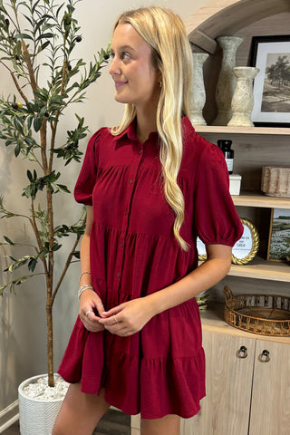 Woman wearing a red dress standing in a room with decorative elements.
