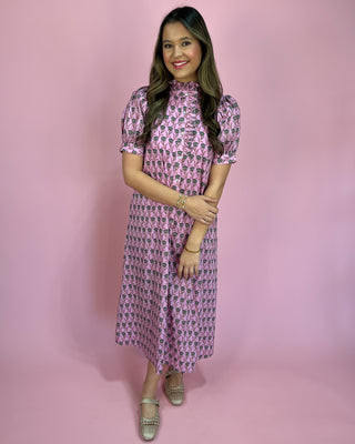 Woman wearing a pink patterned dress against a pink background